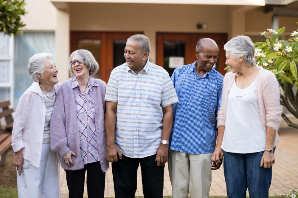 Cheerful senior men and women standing at senior living community