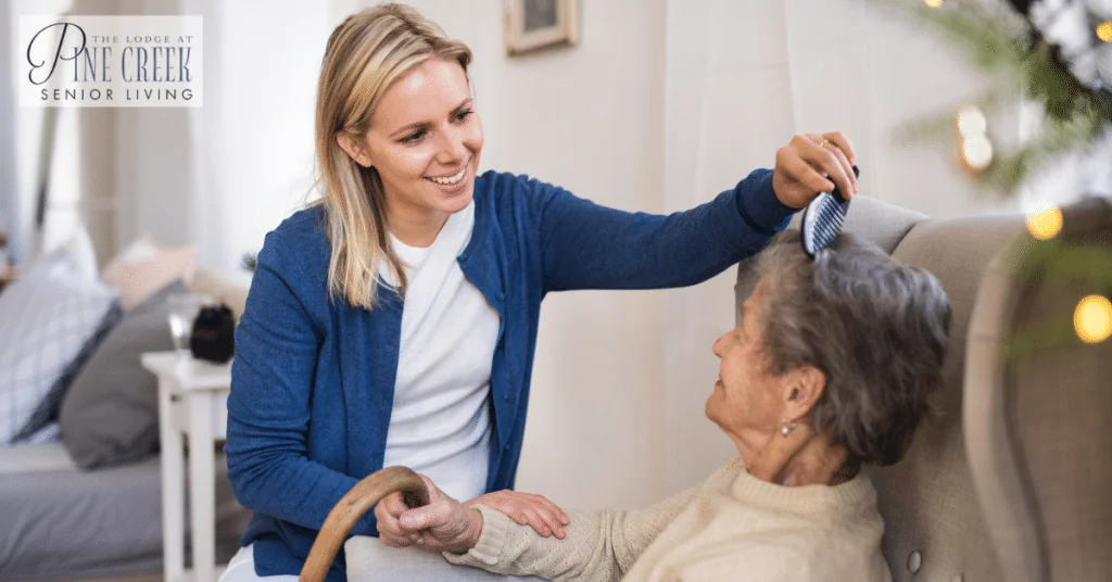 A care partner is combing hair of a senior woman. Memory care services. Assistance with activities of daily living.