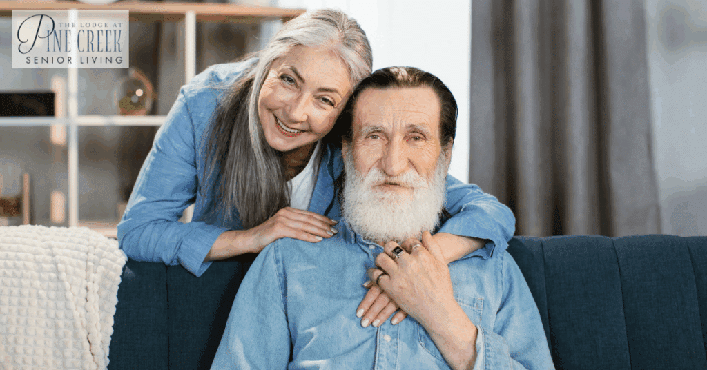 Memory care residents smiling together while sitting on a couch, showcasing companionship and happiness.