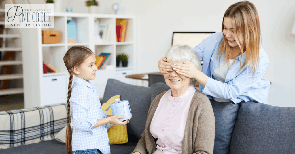 Memory care residents enjoying family time as a grandmother receives a surprise gift from her daughter and granddaughter.